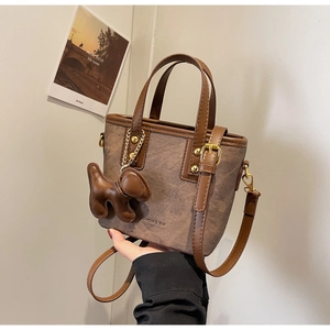 Brown faux leather trapezoid bucket bag with dog charm and fashion text print