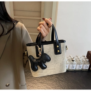 Detail of beige canvas tote bag with black leather trim and cute puppy charm