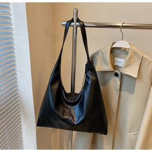 Detail of the soft black leather texture and vertical stitching on the large tote bag