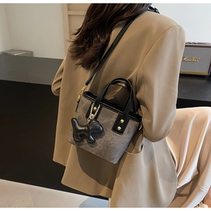 Detailed view of gray bucket bag with black leather trim and cute puppy charm on model