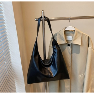 Macro detail of large black soft leather tote bag showing smooth texture and slouchy drape