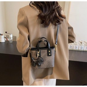 Detail of grey textured bucket bag with black handles and a small dog charm