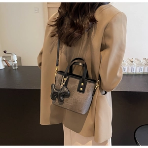 Detail of retro bucket bag with gold rivets, puppy charm and adjustable strap on model