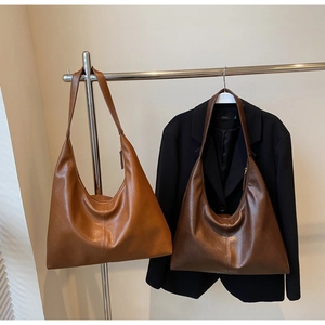 Close-up of caramel and brown leather hobo tote bags with wide shoulder straps
