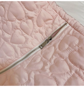 Detail of pink heart-quilted fabric texture and premium silver metal zipper slider