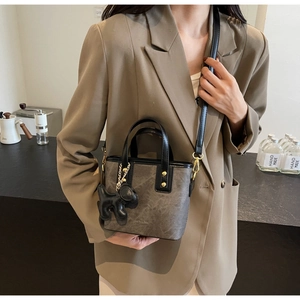 Detail of vintage rock texture tote bag with a 3D dog charm on a khaki blazer
