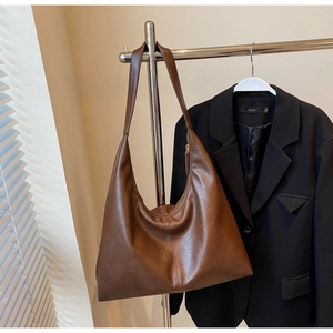 Detail of the soft brown leather tote bag with wide shoulder strap in office setting