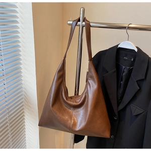 Detail of dark brown leather tote bag showing smooth texture and high-quality hardware