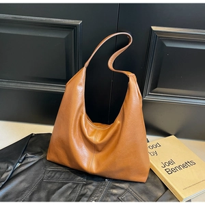 Detail view of the soft caramel brown faux leather texture and stitching on the tote bag