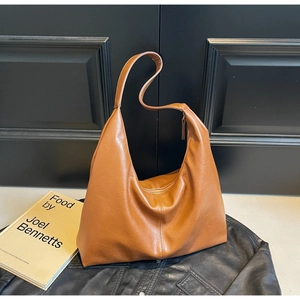 Detailed texture of brown leather hobo bag with zip closure on black jacket background
