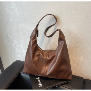Detail of vintage brown hobo bag with oily leather texture and zip closure on black sofa