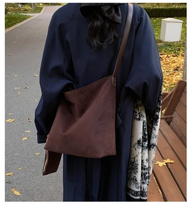 Detail of dark brown suede tote bag and matching pouch shown in autumn park setting