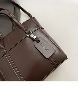 Dettaglio della borsa a secchiello marrone scuro con cuciture a quadri e logo decorativo