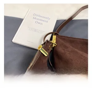 Detail of premium gold hardware and zipper on dark brown matte suede shoulder bag