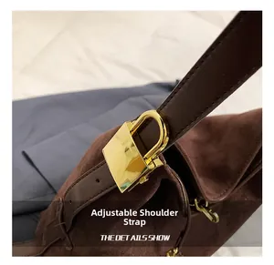 Close-up of adjustable shoulder strap with gold metal buckle on suede tote bag