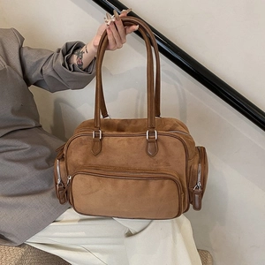 Brown suede Boston shoulder bag with silver zippers and long handles shown with a model