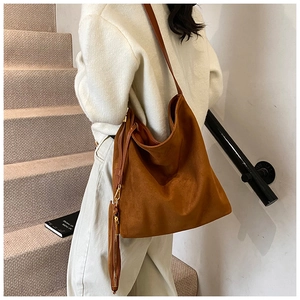 Grand sac seau hobo marron en daim avec pochette zippée assortie porté par le mannequin