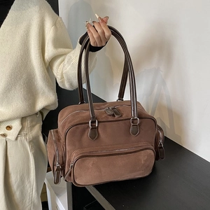 Vintage brown suede shoulder bag with multi-pocket design held by a person