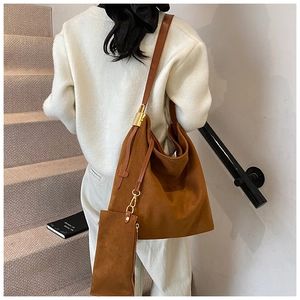 Détail du sac cabas en daim marron avec crochets dorés et pochette assortie