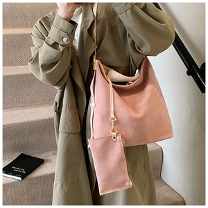 Grand sac cabas rose poudré avec pochette assortie porté par un mannequin