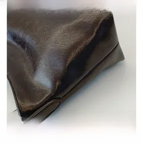 Makroaufnahme der Lederstruktur und silbernen Hardware einer braunen Beuteltasche