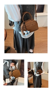 Brown Boston bag with double handles and a blue pony charm in a home setting