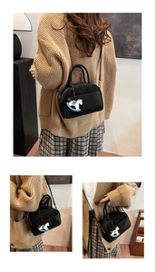 Detail of a black crossbody bag with a cute tricolor rocking horse charm on a model