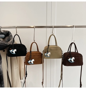 Detail view of bowling bags in matte finish with a horse pendant and shoulder straps
