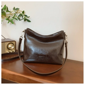 Detail der Vintage braunen Ölwachs-Ledertasche mit Metall-Logo und glatter Textur