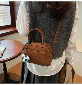 Detail shot of a matte brown leather bowling bag featuring a cute rocking horse charm