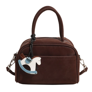 Detail of matte brown bowling bag featuring dual handles and blue rocking horse charm