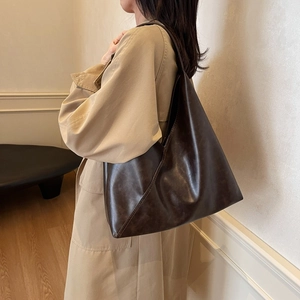 Brown large capacity vintage shoulder tote bag worn with a beige trench coat