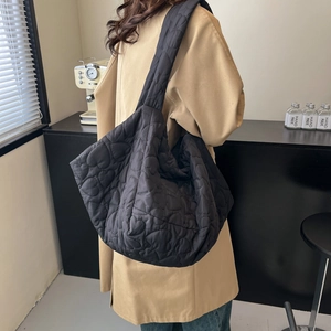 Large black heart-quilted tote bag for women showing spacious commuter shoulder style