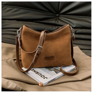 Nahaufnahme der verstellbaren Schnalle und des Logos auf der braunen Wildledertasche