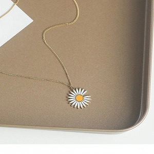 Collier marguerite pour femme en acier doré avec pétales blancs sur un plateau