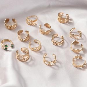 Detail of 12-piece bohemian gold rings set with sun moon motifs and green gems