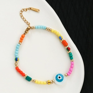 Close-up of bohemian colorful beads with blue evil eye charm and 18K gold clasp detail