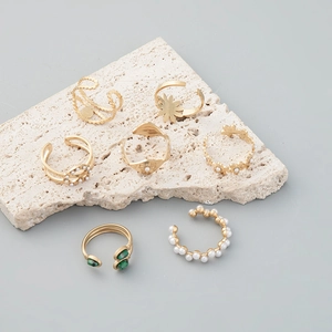Set of 7 gold 14K rings with pearls and sun engraving on travertine stone display