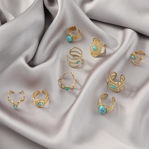 Nine-piece vintage gold stainless steel rings with turquoise stones on grey silk fabric