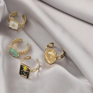 Detailed view of four vintage gold-plated rings with colorful enamel on silk background