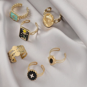 Macro shot of six gold-plated tarot and star rings set on grey luxury satin fabric