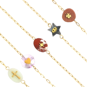 Détail de cinq bracelets en chaîne trombone dorée avec divers pendentifs en pierre naturelle