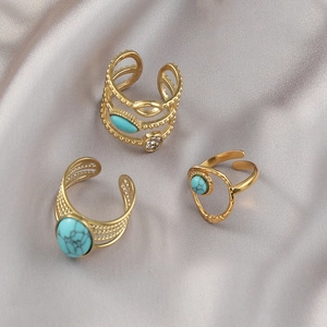 Three-piece gold bohemian ring set with turquoise stones and zircons on grey silk