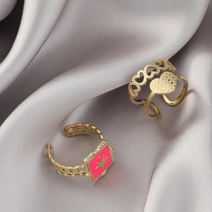 Detail of 14K gold plated rings with pink enamel star and hollow heart patterns