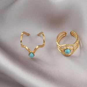 Detail of vintage gold wide rings with turquoise stones on gray satin fabric