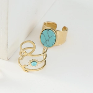 Detail of gold-plated rings with turquoise stone and bohemian celestial symbols