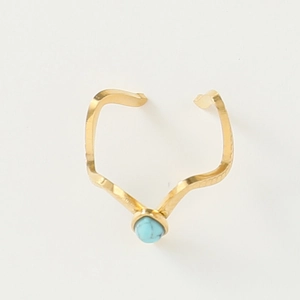 Macro detail of wave-shaped golden ring with center-mounted round blue turquoise stone