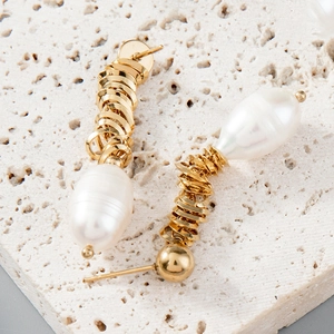 Threaded gold stainless steel earrings with white Baroque pearls on stone background