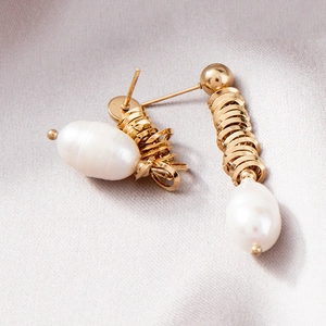 Golden spiral hoop earrings with baroque freshwater pearls on purple silk fabric