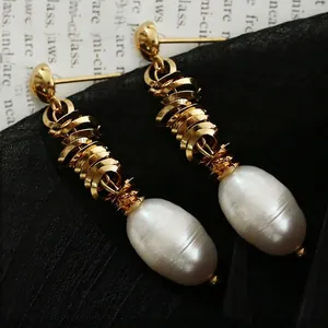 Elegant gold spiral stainless steel earrings with white Baroque pearls on silk background